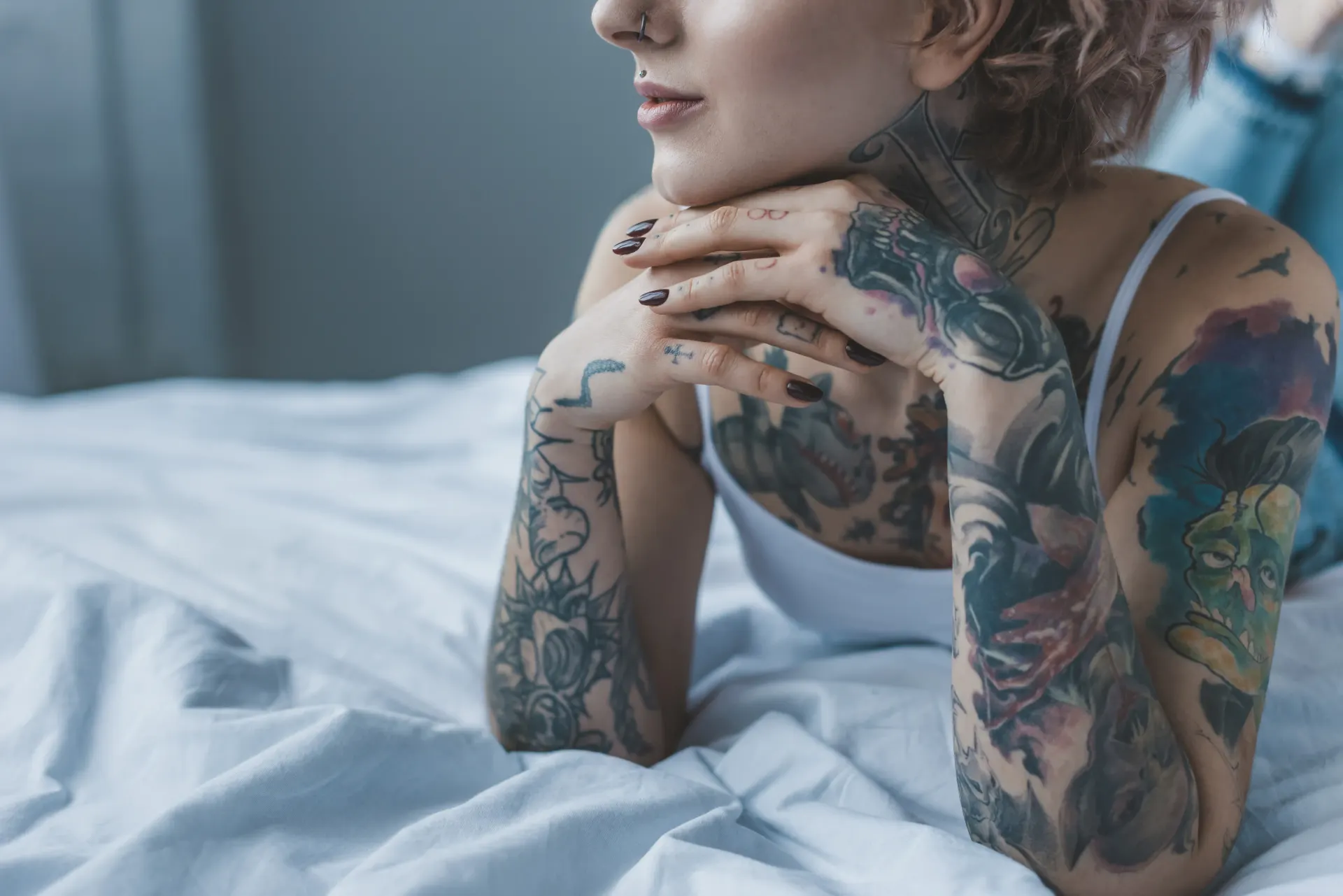 Tätowierte Frau liegt entspannt auf einem Bett